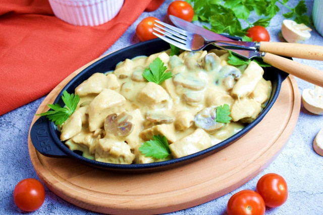 Chicken fillet with mushrooms in a frying pan in sour cream