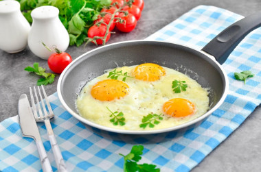 Fried eggs with cheese in a frying pan