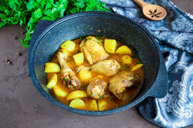 Stewed chicken with potatoes in a cauldron on the stove