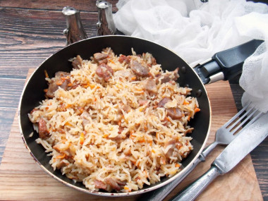 Rice with stewed meat in a frying pan