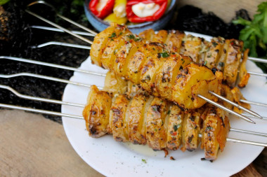 Potatoes with bacon on skewers on the grill