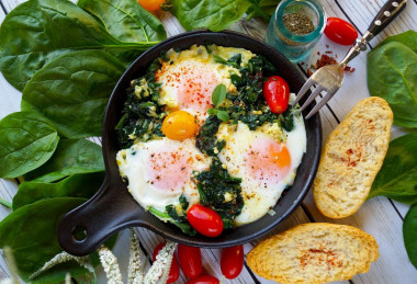 Spinach with egg in a frying pan