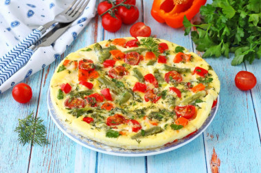 Omelet with vegetables, cheese and herbs in a frying pan