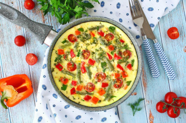 Omelet with vegetables, cheese and herbs in a frying pan