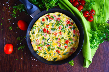 Omelet with zucchini and tomatoes in a frying pan