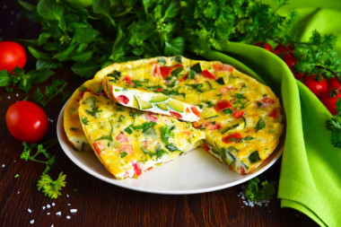 Omelet with zucchini and tomatoes in a frying pan