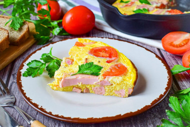 Omelet in a frying pan with sausage and cheese