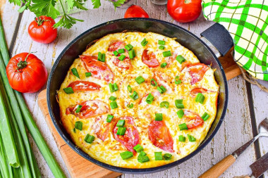 Omelet with tomatoes and cheese in a frying pan