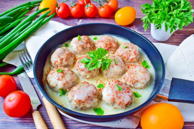 Meatballs in sour cream sauce in a frying pan