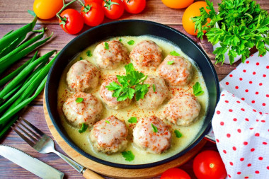 Meatballs in sour cream sauce in a frying pan