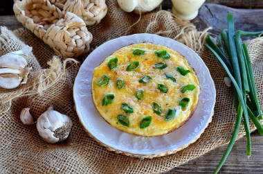 Omelet with green onions in a frying pan