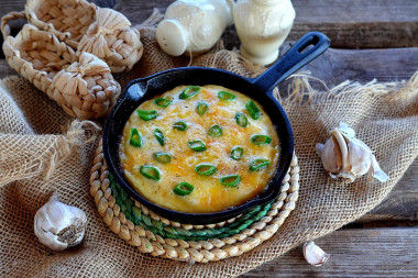 Omelet with green onions in a frying pan