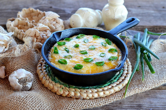 Omelet with green onions in a frying pan