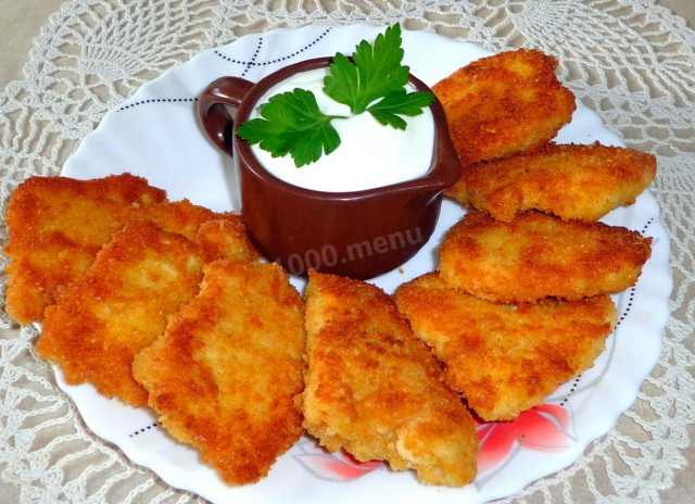 Breaded chicken breasts in a frying pan