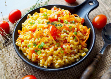 Bulgur with onions and carrots in a frying pan