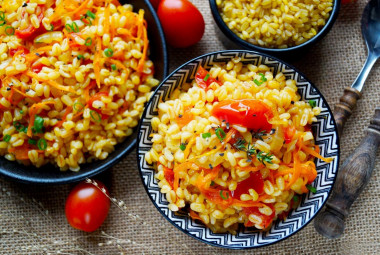 Bulgur with onions and carrots in a frying pan