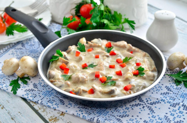 Meat with mushrooms in sour cream sauce in a frying pan