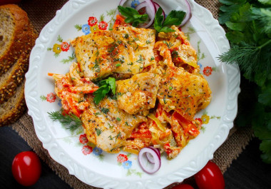 Pangasius with vegetables and sour cream in a frying pan