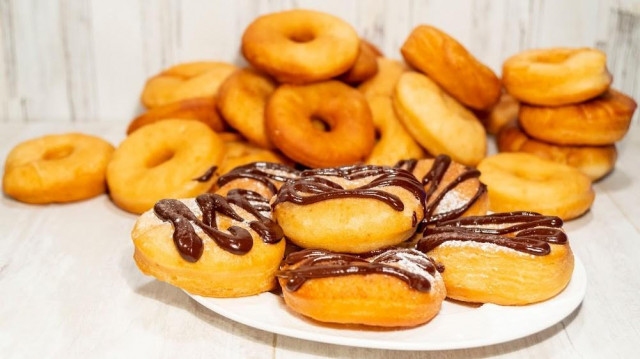 Airy sweet deep-fried doughnuts with frosting on milk