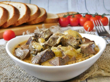 Pork liver in sour cream with onions in a frying pan