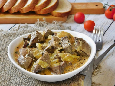 Pork liver in sour cream with onions in a frying pan