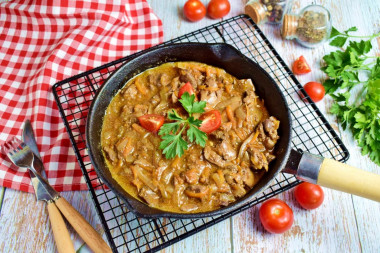 Chicken liver with gravy in a frying pan with onions