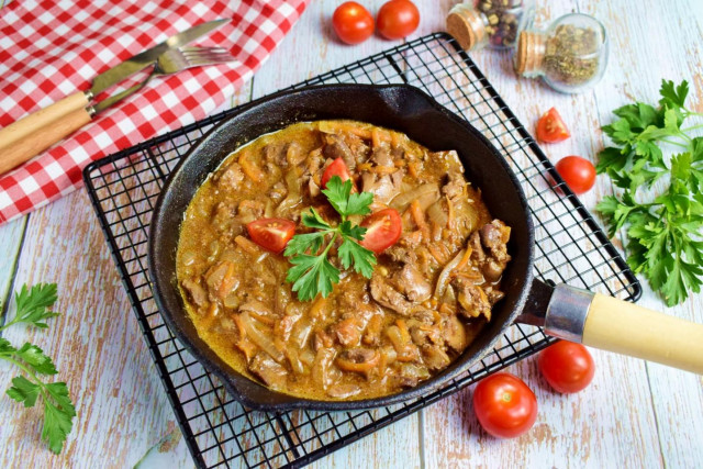 Chicken liver with gravy in a frying pan with onions