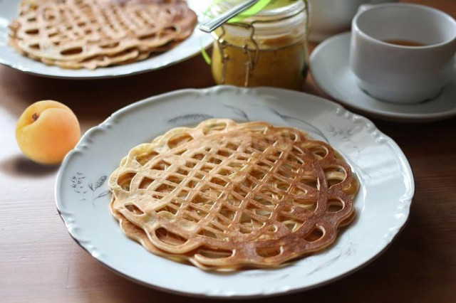 Thin fishnet pancakes on boiling water