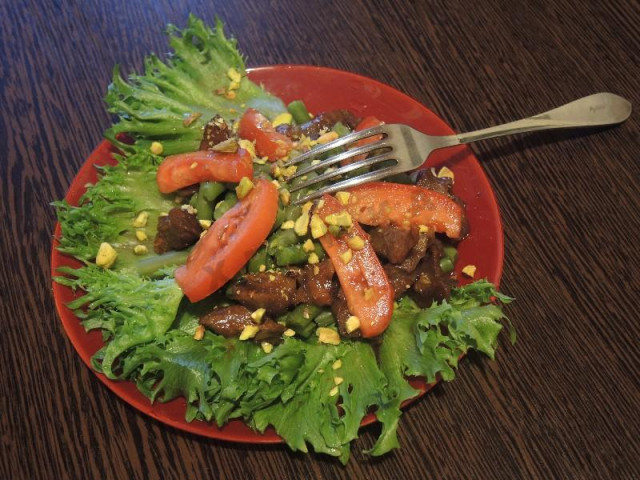 The salad is warm with beef, nuts and vegetables