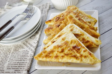 Triangles of pita bread with egg and cheese in a frying pan