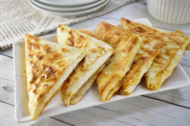 Triangles of pita bread with egg and cheese in a frying pan