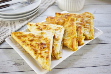 Triangles of pita bread with egg and cheese in a frying pan