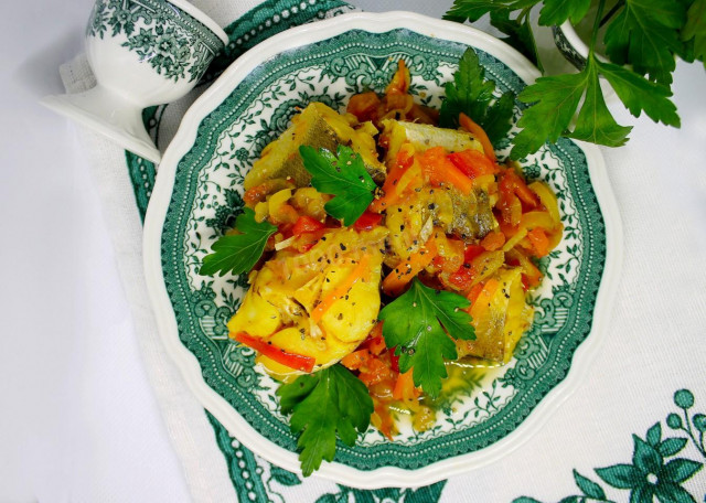 Stewed hake with onions, carrots and vegetables in a frying pan