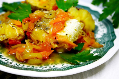 Stewed hake with onions, carrots and vegetables in a frying pan