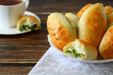 Yeast pies with green onion and egg in the oven