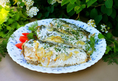 Fried crucian carp in sour cream in a frying pan