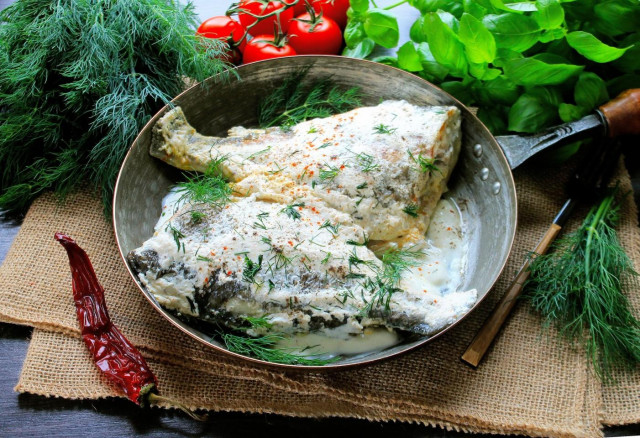 Fried crucian carp in sour cream in a frying pan