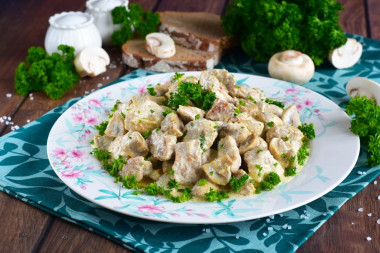 Pork in sour cream sauce with mushrooms in a frying pan