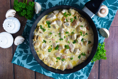 Pork in sour cream sauce with mushrooms in a frying pan