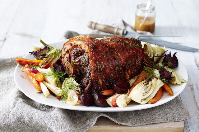 Pork on a bone with vegetables and herbs in the oven