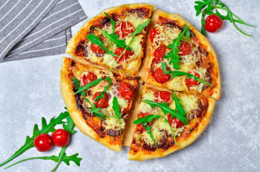 Pizza in the oven with sausage, cheese and tomatoes