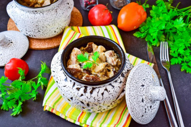 Pork meat in pots in the oven with mushrooms and cheese