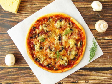 Pizza with champignons sausage and cheese in the oven