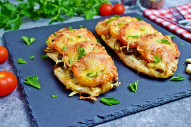 Chicken breast with mushrooms, cheese and tomatoes in the oven