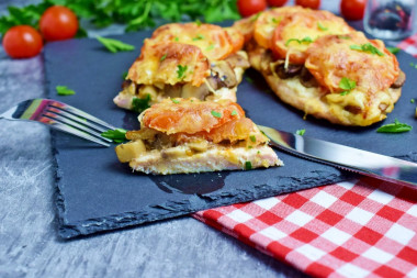 Chicken breast with mushrooms, cheese and tomatoes in the oven