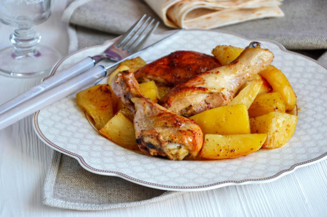 Chicken on a baking sheet in the oven with potatoes