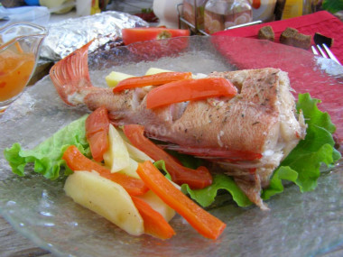 Sea bass baked with potatoes in the oven in foil