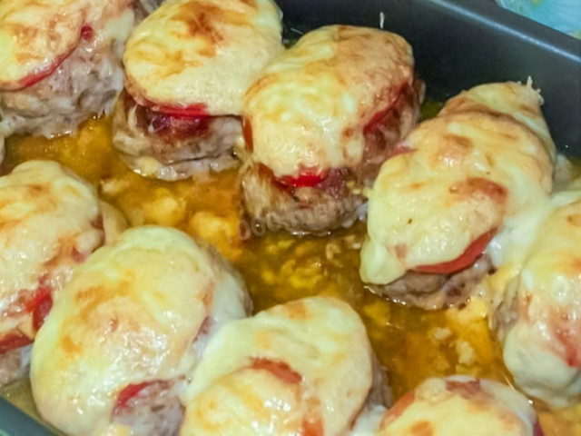 Cutlets under a fur coat baked in the oven with tomatoes