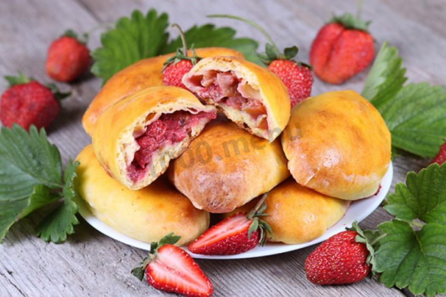 Delicious yeast pies with fresh strawberries in the oven