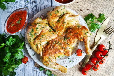 Tobacco chicken in a frying pan with a crispy crust